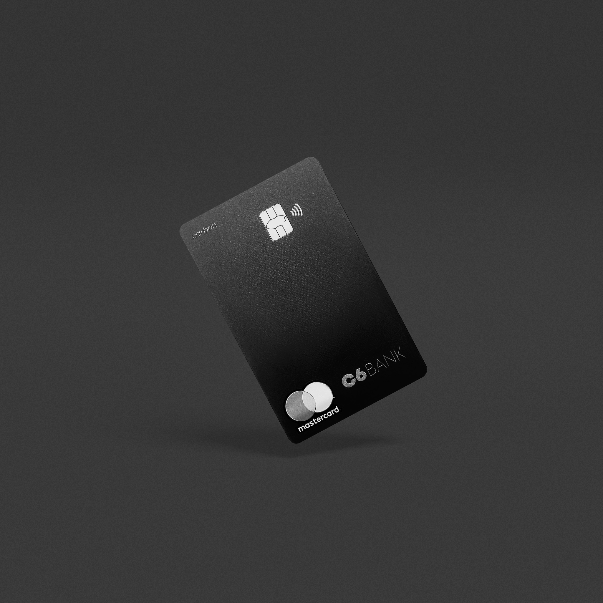 Foto de um cartão C6 Carbon de frente, na vertical, um pouco inclinado, num fundo preto.