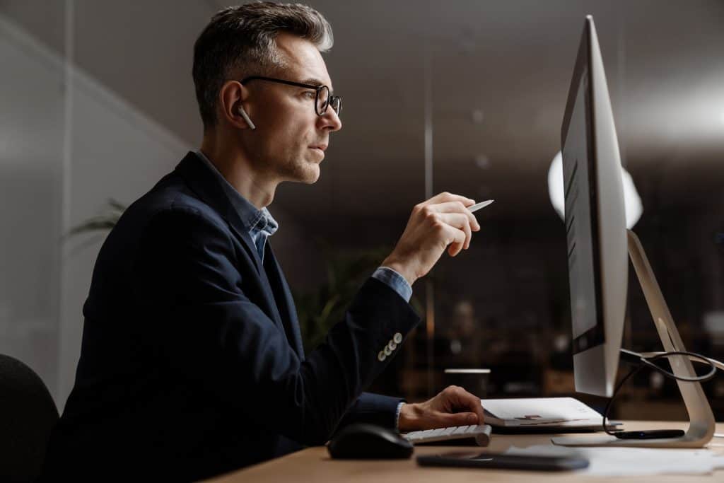 homem branco e grisalho mexendo em um grande computador lendo sobre ações ordinárias e preferenciais