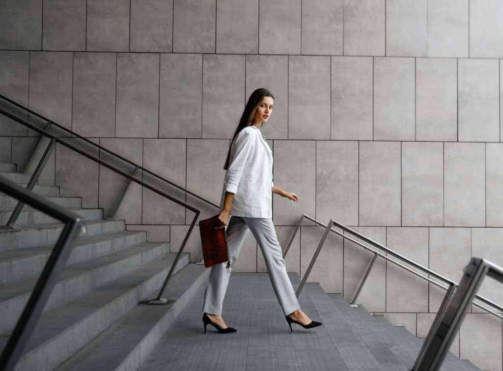 Mulher com roupas formais descendo escadas com maleta na mão enquanto pensa sobre a política monetária do Brasil